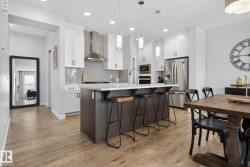 Well-appointed kitchen featuring a large island with a countertop, white cabinetry, and stainless steel appliances - 