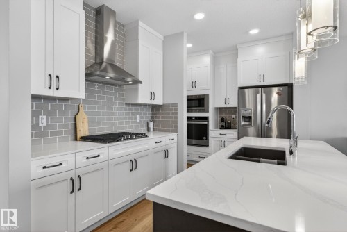 Modern kitchen featuring white cabinetry, light countertops, stainless steel appliances, and a grey subway tile backsplash - 3230 Parker Loop, Edmonton, AB - Indoor Photo Showing Kitchen With Double Sink With Upgraded Kitchen