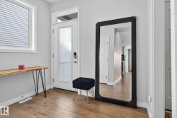Entryway featuring hardwood floors, a white door with frosted glass, and a window with horizontal blinds - 
