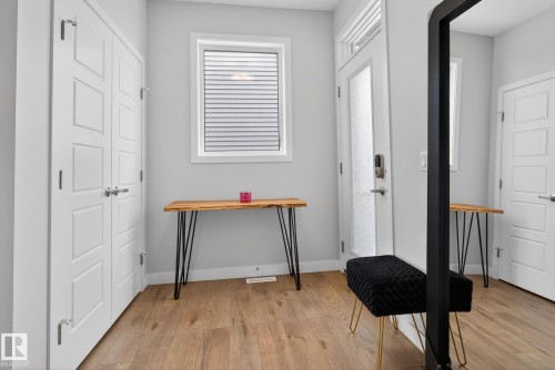 The entry features light wood flooring, white paneled doors, and a window with horizontal blinds - 3230 Parker Loop, Edmonton, AB - Indoor Photo Showing Other Room