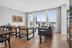 Living area featuring light hardwood flooring, large windows with white curtains, recessed lighting, and a view of the outdoors - 