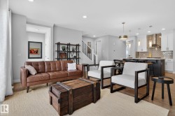 Open concept living area featuring light-toned flooring, recessed lighting, and a view of the kitchen with pendant lighting - 