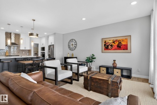 Open concept living area featuring a kitchen with stainless steel appliances, a breakfast bar, and pendant lighting - 3230 Parker Loop, Edmonton, AB - Indoor