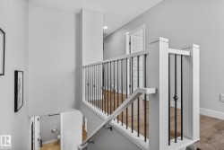 The property features a staircase with white newel posts and handrails, complemented by black iron balusters - 