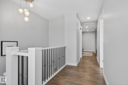 Hallway featuring light wood-style flooring, recessed lighting, and a modern chandelier - 