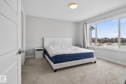 The property features a bright room with carpeted flooring, a large window providing views of the surrounding neighborhood, and neutral wall paint - 