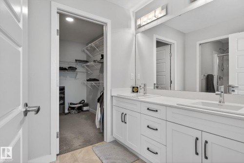 Bathroom featuring a dual vanity with white cabinetry and chrome fixtures, illuminated by a light bar above the mirror - 3230 Parker Loop, Edmonton, AB - Indoor Photo Showing Bathroom