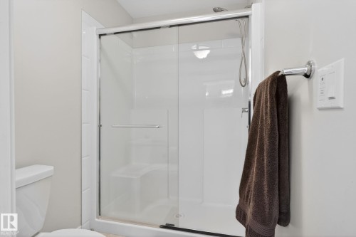 The bathroom features a shower enclosure with a clear glass sliding door and a white shower base - 3230 Parker Loop, Edmonton, AB - Indoor Photo Showing Bathroom