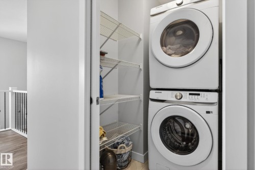 The property includes a laundry area with a stacked washer and dryer, along with open wire shelving for storage - 3230 Parker Loop, Edmonton, AB - Indoor Photo Showing Laundry Room