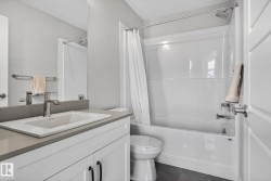 This bathroom features a contemporary vanity with a rectangular sink and a single-handle faucet, set against light-colored walls - 