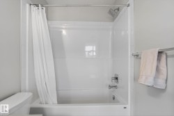 Bathroom featuring a bathtub and shower combination with a white shower curtain, a shower head, and a chrome faucet - 