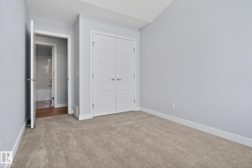 This room features neutral-toned carpeting, a closet with white paneled bifold doors, and light gray walls - 3230 Parker Loop, Edmonton, AB - Indoor Photo Showing Other Room