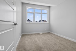 This room features neutral-toned carpet, a white door with silver hardware, and a window providing natural light - 