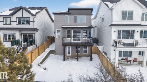 The property features a contemporary gray exterior with a walk-out deck and a snow-covered yard - 3230 Parker Loop, Edmonton, AB - Outdoor With Facade