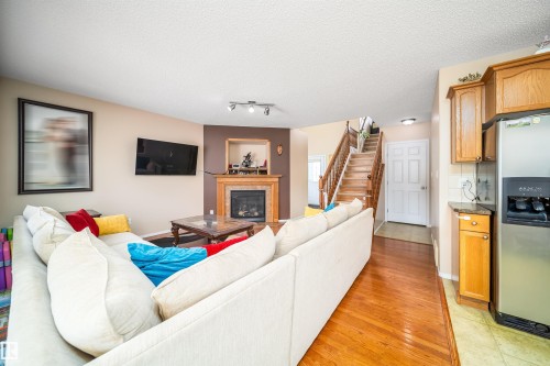 Living area featuring hardwood flooring, a fireplace with a wood mantle, and a staircase with wood banisters - 8932 175 Avenue, Edmonton, AB - Indoor Photo Showing Living Room With Fireplace