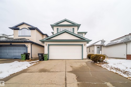 The property features a two-story exterior with light-colored siding and dark trim, a front-facing garage, and a concrete driveway - 8932 175 Avenue, Edmonton, AB - Outdoor With Facade