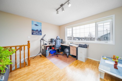 This versatile space features light-toned flooring, a large window providing views of the neighborhood, and a wooden banister - 8932 175 Avenue, Edmonton, AB - Indoor Photo Showing Other Room
