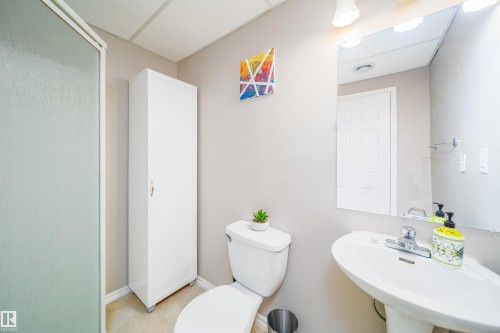 The bathroom features a shower with a translucent glass door, a pedestal sink, and a mirrored vanity with overhead lighting - 8932 175 Avenue, Edmonton, AB - Indoor Photo Showing Bathroom
