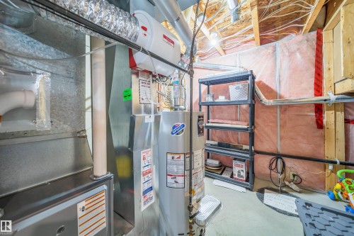 Utility area featuring exposed wooden joists, insulated walls, and a water heater - 8932 175 Avenue, Edmonton, AB - Indoor Photo Showing Basement