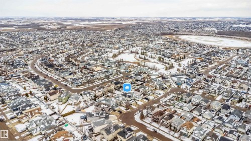 Aerial view of the neighborhood showcasing residential properties with snow-covered roofs, winding streets, and a frozen body of water - 8932 175 Avenue, Edmonton, AB - Outdoor With View