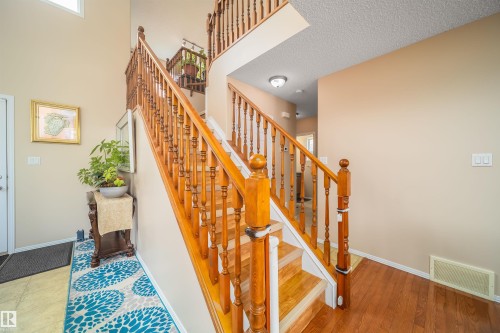 This property features a grand wooden staircase with a balustrade, light-colored walls, and hardwood flooring - 8932 175 Avenue, Edmonton, AB - Indoor Photo Showing Other Room
