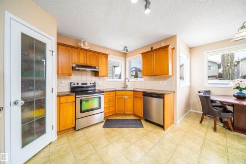 The kitchen features wooden cabinetry, stainless steel appliances, and a tiled backsplash - 8932 175 Avenue, Edmonton, AB - Indoor Photo Showing Kitchen