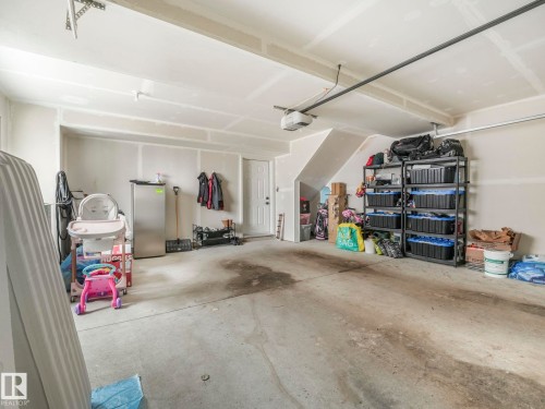 Spacious garage with a concrete floor, painted walls, and an overhead garage door opener - 95 1010 Rabbit Hill Road, Edmonton, AB - Indoor Photo Showing Garage