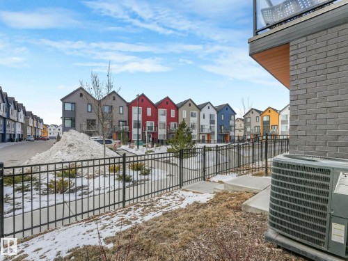 View of the neighborhood featuring a paved road, sidewalks, and a variety of colorful row houses - 95 1010 Rabbit Hill Road, Edmonton, AB - Outdoor