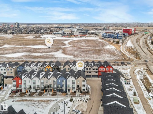 Aerial view of the property and surrounding neighborhood, featuring townhouses with distinct rooflines and a well-maintained road network - 95 1010 Rabbit Hill Road, Edmonton, AB - Outdoor With View