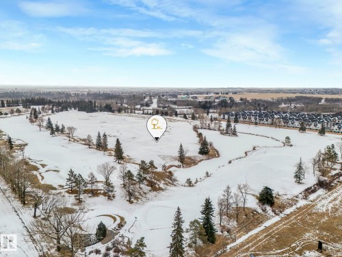 This property offers expansive views of a snow-covered landscape with scattered evergreen and deciduous trees, and a distant community of residential buildings - 95 1010 Rabbit Hill Road, Edmonton, AB - Outdoor With View