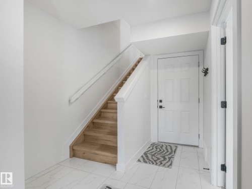 Entryway featuring light hardwood stairs with a white railing, a white front door, and tiled flooring - 95 1010 Rabbit Hill Road, Edmonton, AB - Indoor Photo Showing Other Room