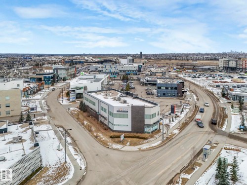 Aerial view of the building at a street corner, featuring a partially snowy landscape, surrounding roads, and various other buildings - 95 1010 Rabbit Hill Road, Edmonton, AB - Outdoor With View