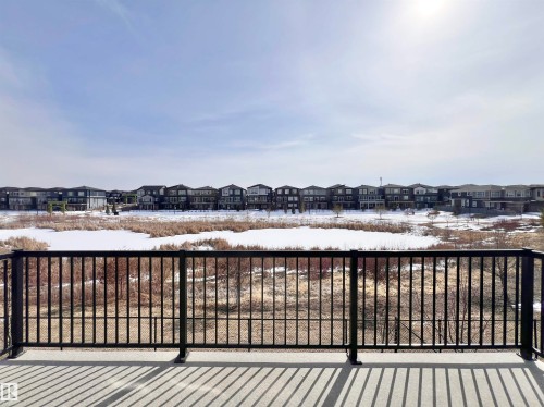 Balcony with a black metal railing overlooking a snow-covered landscape with a body of water and distant properties - 6055 King Landing Landing, Edmonton, AB - Outdoor With View