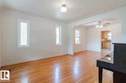 Living area featuring hardwood floors, decorative windows, and an arched entryway leading to an additional space - 