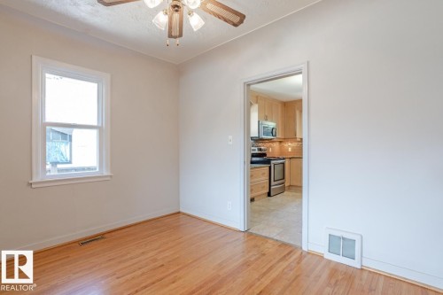The room features hardwood floors and a ceiling fan, with a window providing natural light - 8736 76 Avenue, Edmonton, AB - Indoor Photo Showing Other Room