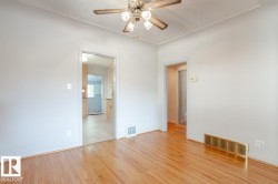 This space features hardwood floors, a ceiling fan, and white walls - 