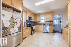 The kitchen features light wood cabinetry, stainless steel appliances, granite countertops, and tile flooring - 