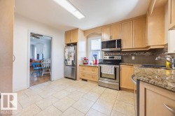 The kitchen features light wood cabinetry, stainless steel appliances, granite countertops, and tile flooring - 