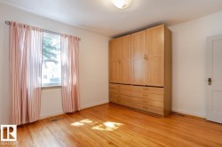 This room features hardwood floors, a prominent window providing natural light, and a built-in wooden storage unit with cabinets and drawers - 