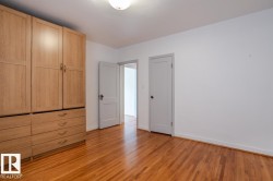 This room features hardwood floors and a white ceiling with a flush-mount light fixture - 