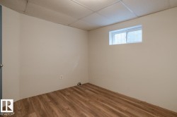 This room features light-colored walls, wood-style flooring, and a window - 