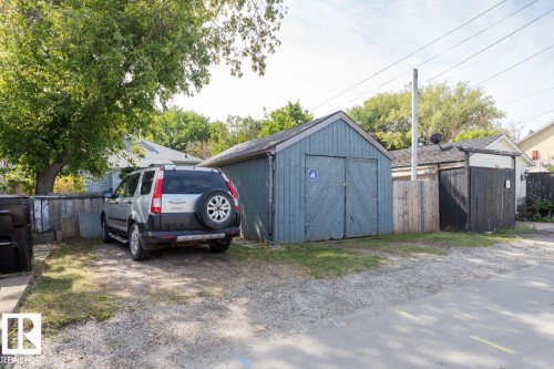 The property features a blue detached shed with double doors and a gravel parking area - 8736 76 Avenue, Edmonton, AB - Outdoor