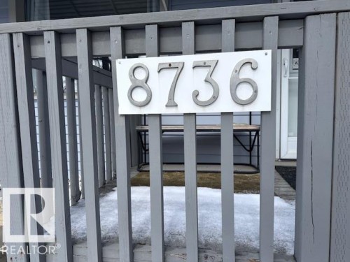 The property features a porch with gray wooden railings and a clearly visible house number display - 8736 76 Avenue, Edmonton, AB - 