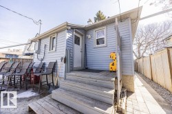 The property features light blue siding, a wooden deck with steps, and a white back door - 