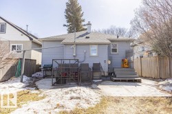 The property features a rear exterior with light blue siding, a grey shingled roof, and a concrete patio - 