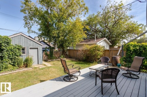 This property features a spacious yard with a well-maintained lawn and mature trees, offering a serene outdoor environment - 8736 76 Avenue, Edmonton, AB - Outdoor With Deck Patio Veranda