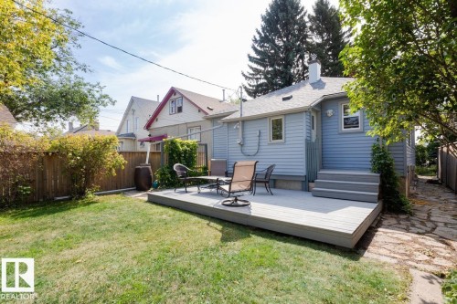 The property features a spacious backyard with a well-maintained lawn and a wooden fence - 8736 76 Avenue, Edmonton, AB - Outdoor With Deck Patio Veranda