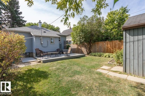 The property features a spacious backyard with a lawn, a wooden deck, and a shed - 8736 76 Avenue, Edmonton, AB - Outdoor With Deck Patio Veranda