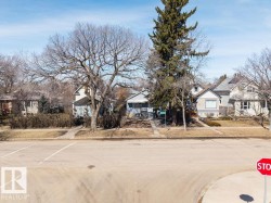 The property is located on a paved street with a sidewalk and features mature trees within its front yard - 
