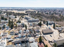 An aerial view of the surrounding neighborhood, featuring a mix of residential properties, mature trees, and paved roads - 